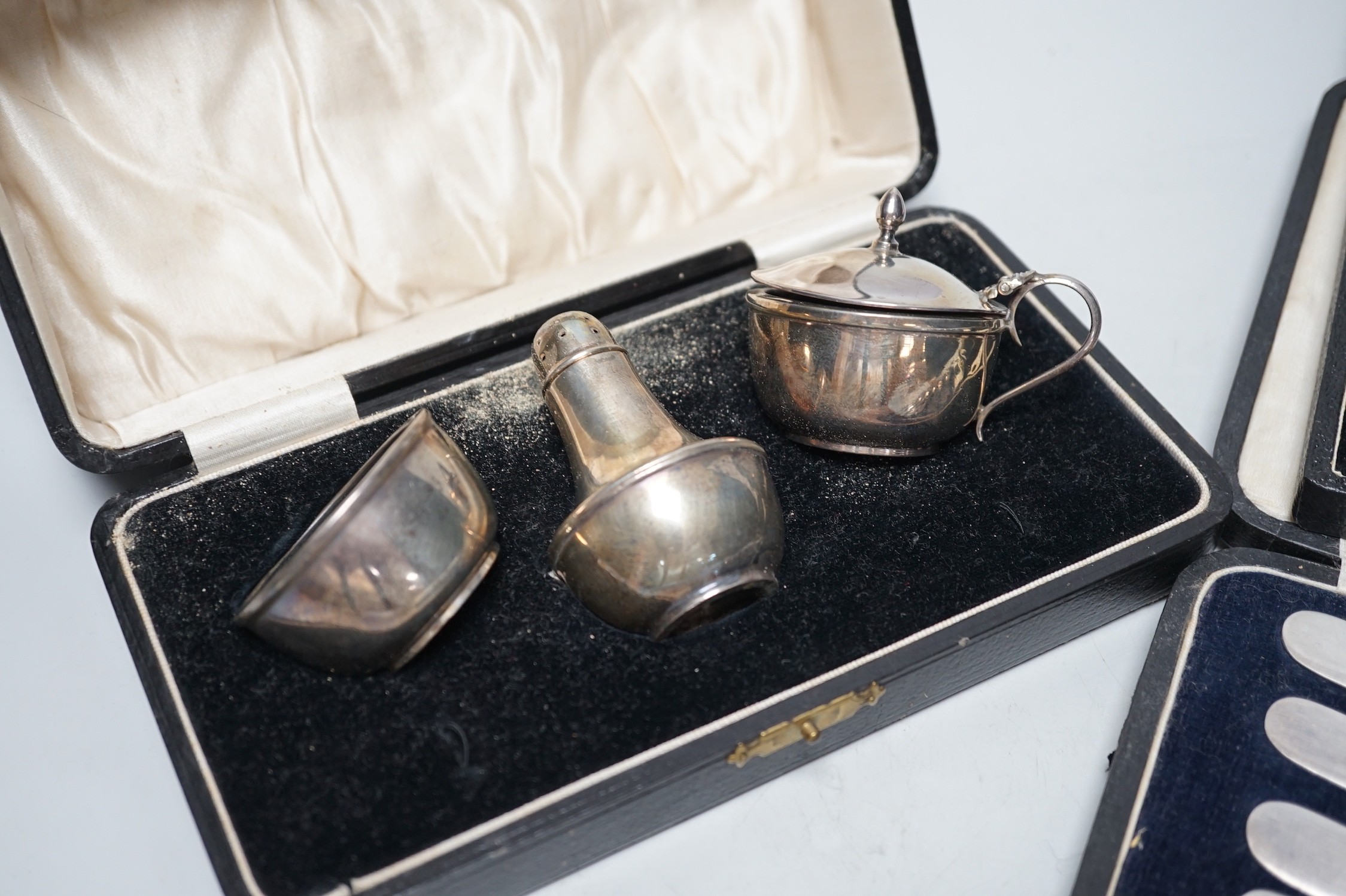 A cased George V three piece silver condiment set, Birmingham, 1928 and two other cased sets of flatware.